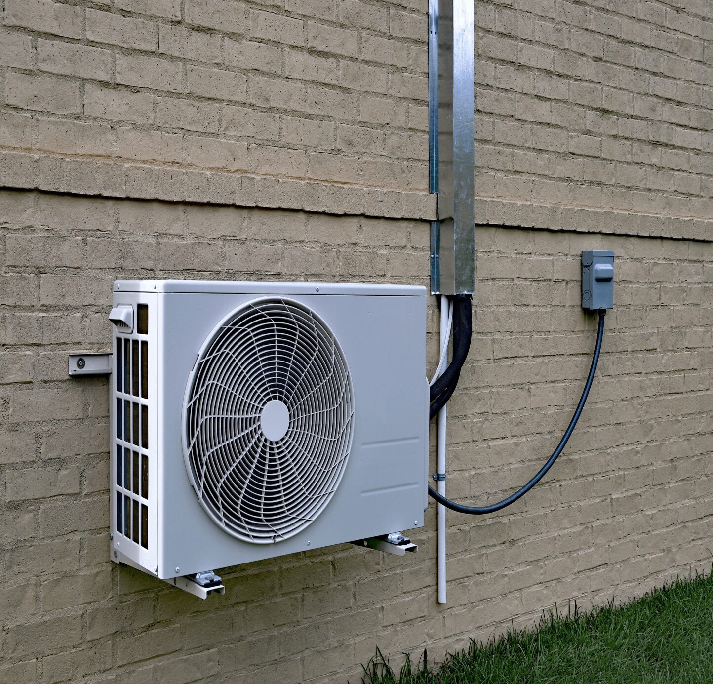 Exterior air conditioning unit on brick wall.