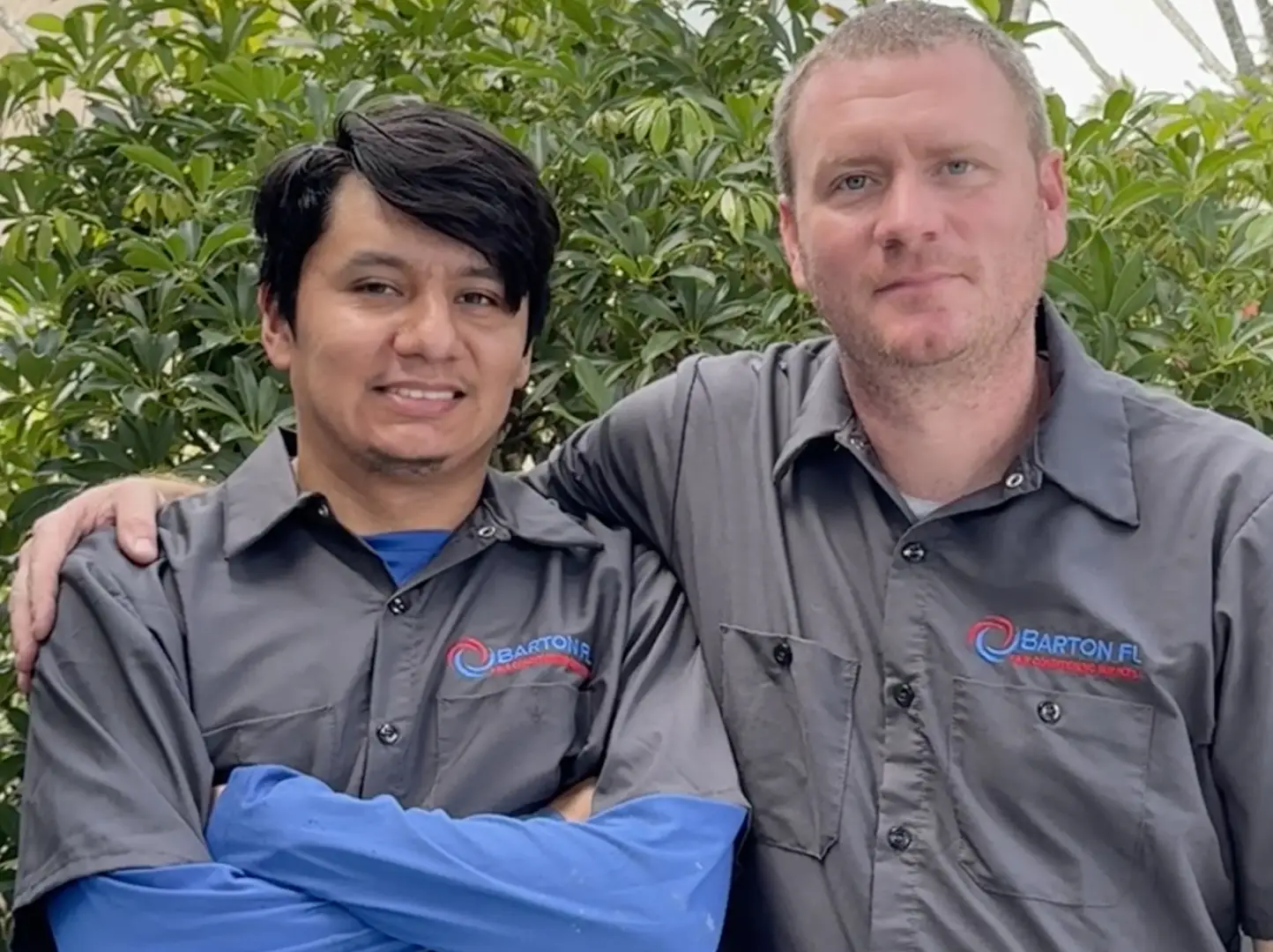 Two men in grey shirts posing for a picture.